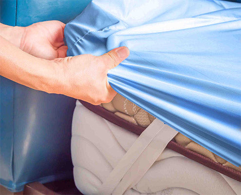 person holding the fitted sheet fitting it on the mattress